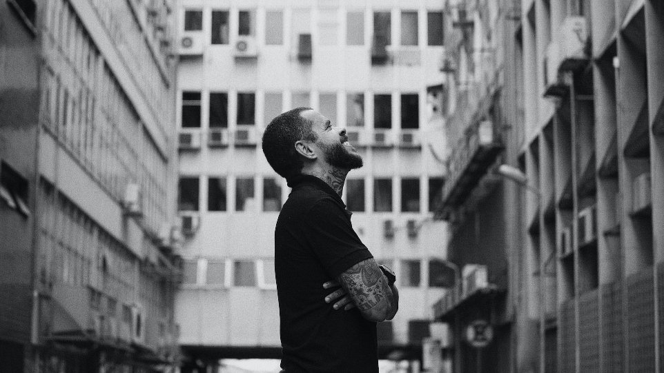 grayscale photo of man standing near building